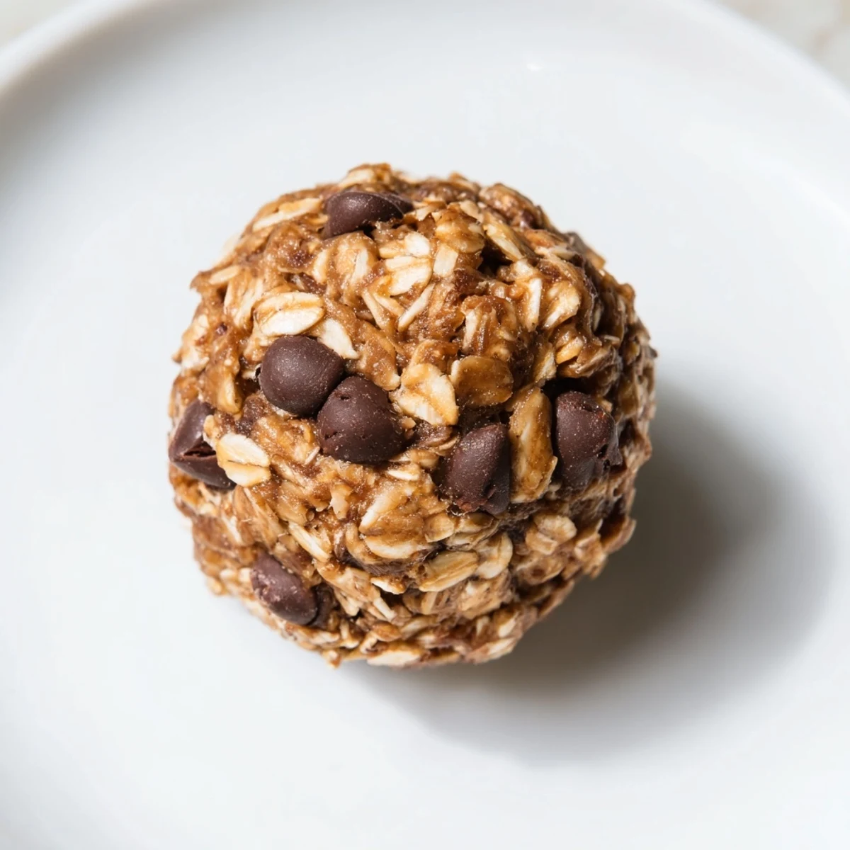 Golden spoonful of delicious No-Bake Peanut Butter Energy Balls, studded with chocolate chips.