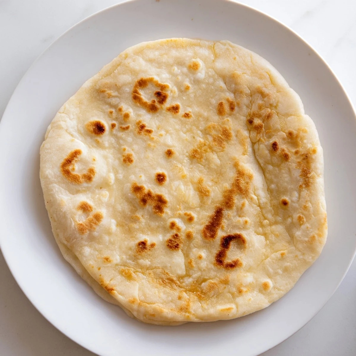A stack of freshly-cooked Three-Ingredient Easy Flatbreads, each with bubbly brown spots, ready to serve.