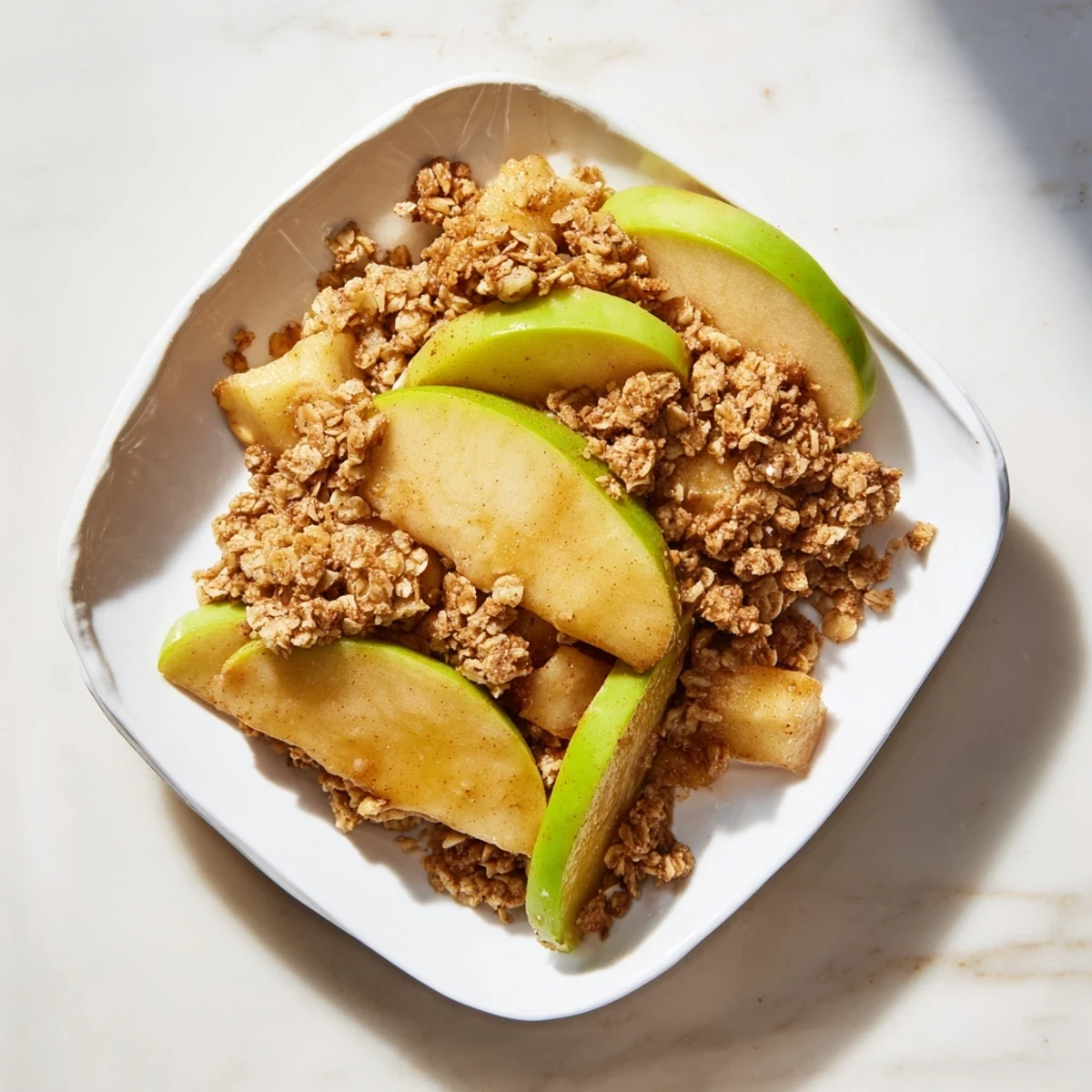 A close-up view of the sweet and rustic Apple and Cinnamon Crumb Bake, perfect with vanilla ice cream.