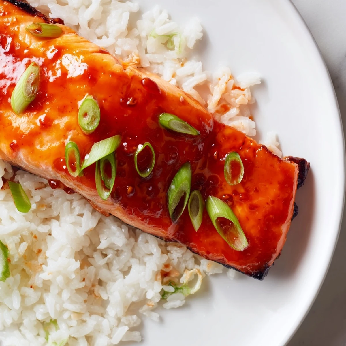 Vibrant image shows flaky, broiled Sticky Orange Salmon topped with green scallions, delicious!