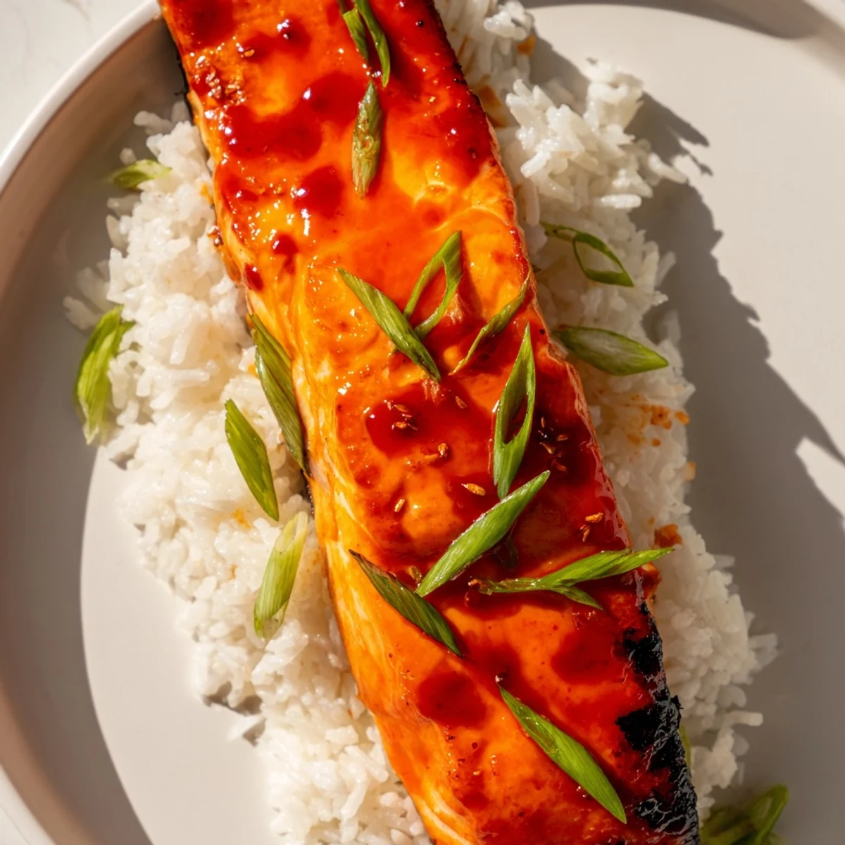 Golden-glazed Sticky Orange Salmon beside a bowl of white rice, fresh and flavorful for dinner.