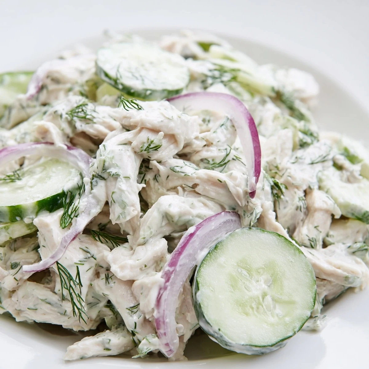 A top-down view of Creamy Cucumber Chicken Salad featuring Greek yogurt dressing, cucumbers, and shredded chicken on a wooden board.