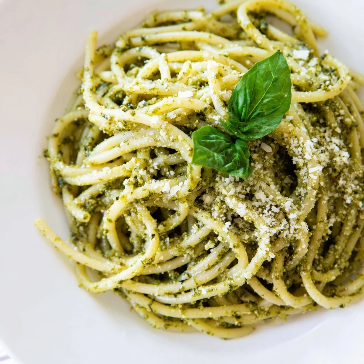 A bowl of creamy sunflower seed pesto pasta tossed with fresh basil and melted Parmesan cheese.  