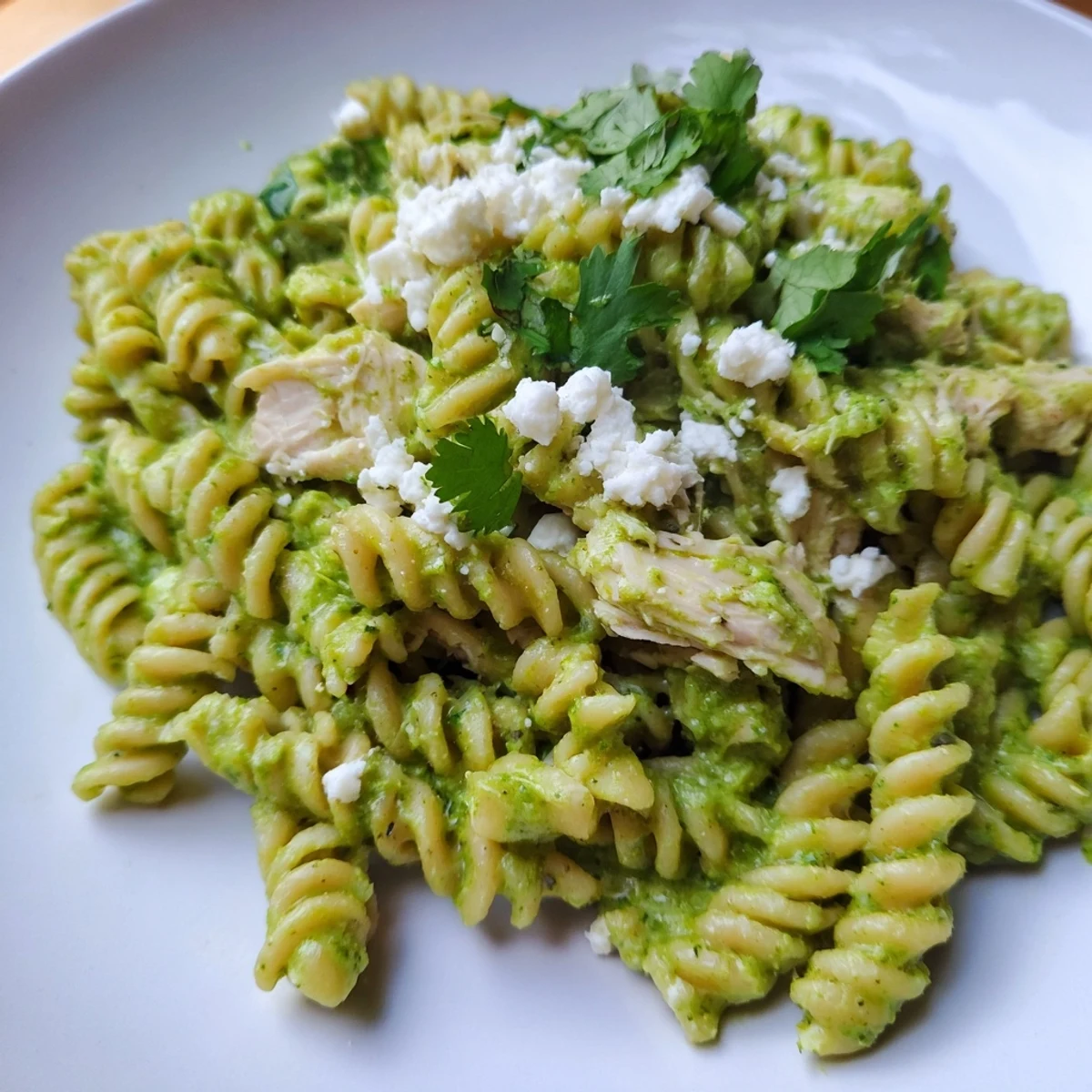 A close-up of Cilantro Lime Chicken Pasta, featuring tender shredded chicken and rotini pasta coated in a tangy, bright green cilantro-lime yogurt sauce.  
