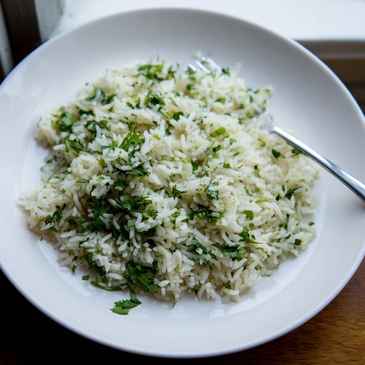A close-up of fluffy Cilantro Lime Rice garnished with fresh cilantro, lime zest, and a lime wedge.