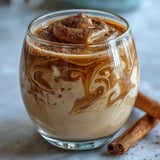 Creamy Guava Coquito with cinnamon garnish in a glass bottle, showcasing the thick, festive Puerto Rican holiday drink.