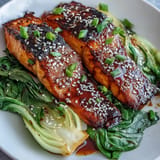 Miso glazed salmon with sesame bok choy, perfectly caramelized and tender, served atop vibrant green stalks.