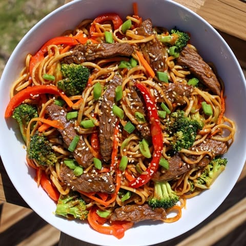 Enjoy a steaming bowl of flavorful easy beef stir-fry with lo mein noodles, perfect for dinner.
