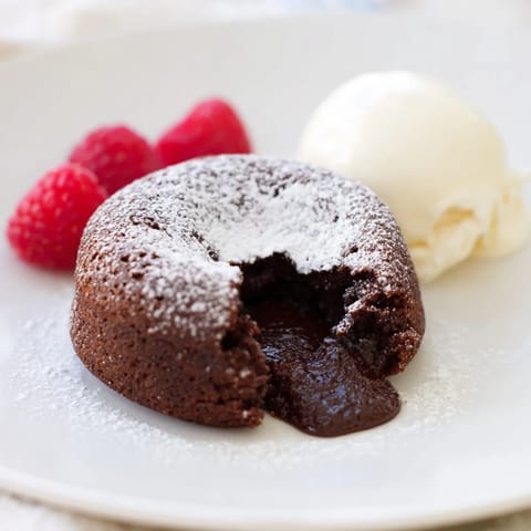 A close-up of a perfectly baked mini chocolate lava cake, ready to serve with powdered sugar.