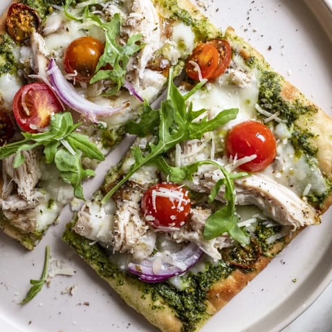 Warm, cheesy Pesto Chicken Flatbread with fresh arugula and basil, a perfect easy dinner.