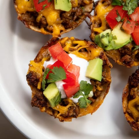 Golden-brown mini taco cups filled with savory ground beef and gooey cheese, a party favorite.