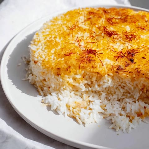 A steaming, fluffy Persian Tahdig rice dish, featuring a beautiful golden crust in the pan.