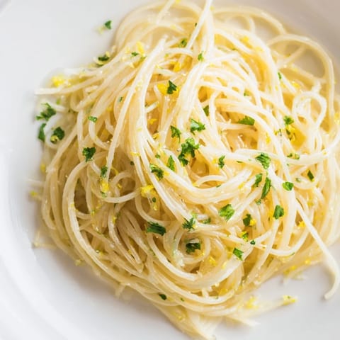 Lemon Butter Pasta Light on a white plate, garnished with fresh parsley and lemon zest.