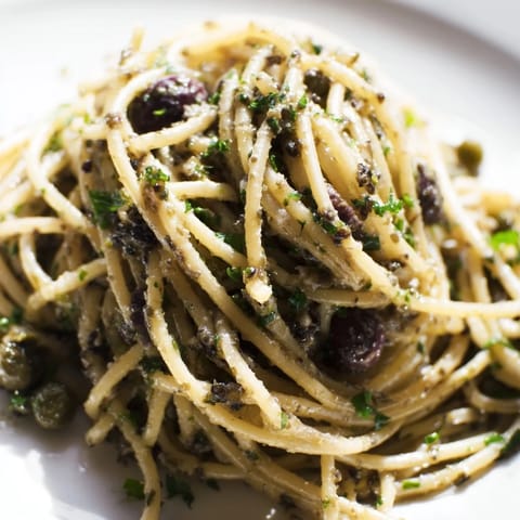 A close-up of Olive Tapenade Pasta with dark olives, bright parsley, and lemon zest on al dente spaghetti.  