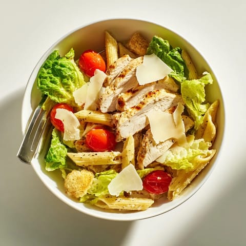 Spicy Chicken Caesar Pasta served warm in a ceramic bowl, topped with shaved Parmesan, croutons, and fresh parsley.