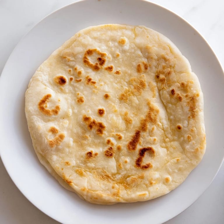 A stack of freshly-cooked Three-Ingredient Easy Flatbreads, each with bubbly brown spots, ready to serve.
