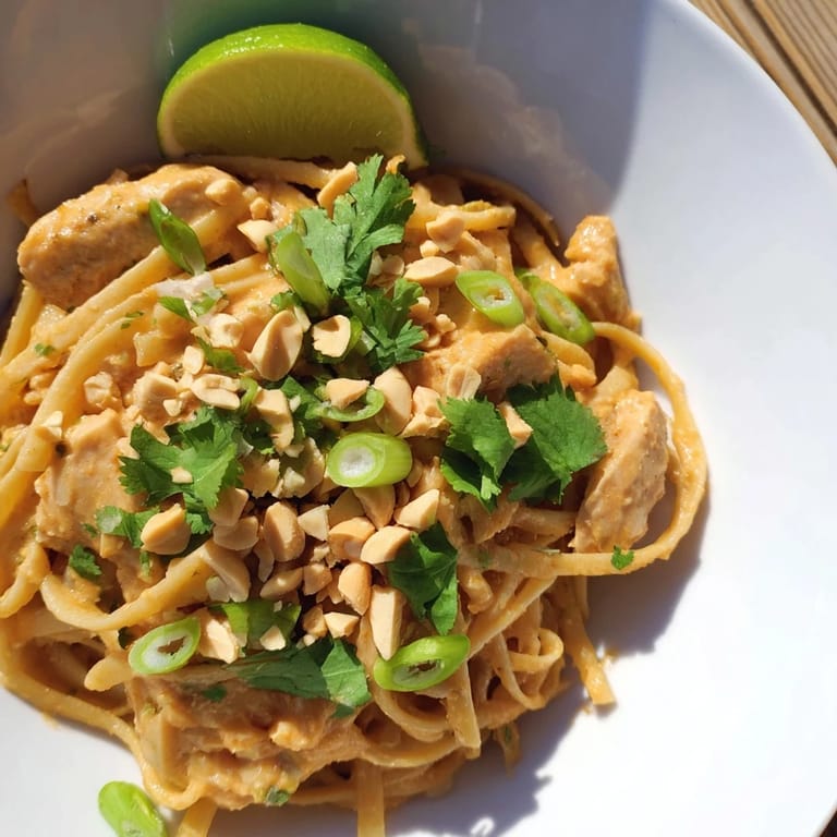 A close-up of savory Thai Peanut Chicken Pasta showing seasoned chicken and linguine tossed in sauce.