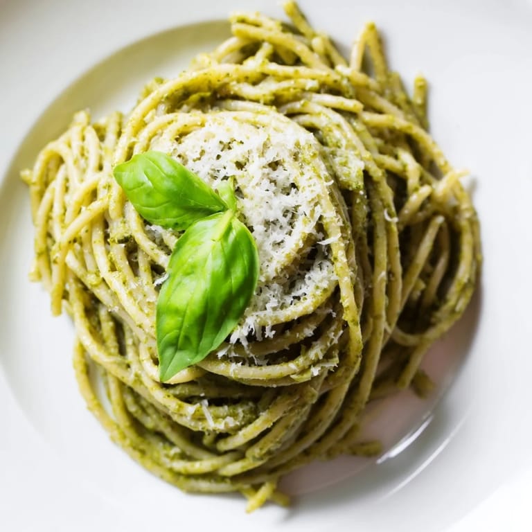 A close-up of creamy sunflower seed pesto pasta with toasted seeds and a sprinkle of extra Parmesan.  