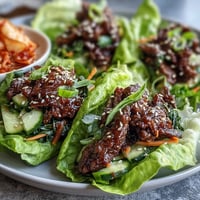Korean BBQ beef wraps glistening, topped with vibrant, spicy kimchi.
